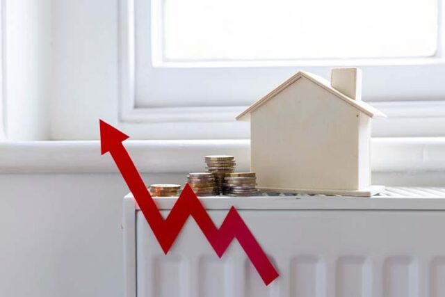 Digital thermostat and radiator showing central heating cost per hour in a UK home